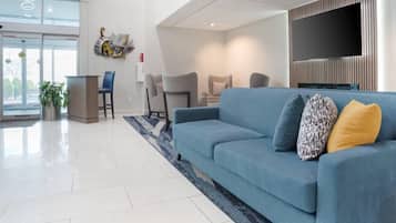 Una sala de estar moderna con un sofá azul, un televisor de pantalla plana y un ventanal grande.
