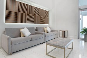 Una sala de estar moderna con un sofá gris, una mesita auxiliar y una mesa de centro con cubierta de mármol.