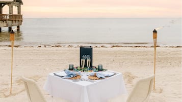 Una mesa de playa con un menú, dos sillas y un antorcha tiki.