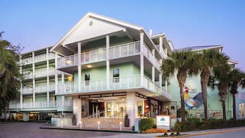 A multi-story hotel with balconies, a central entrance, and a mural of a rooster.