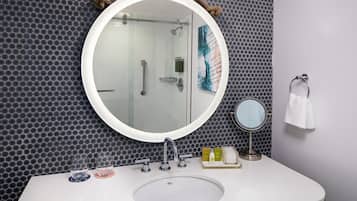 Un baño con un espejo redondo, un lavamanos y una ducha.