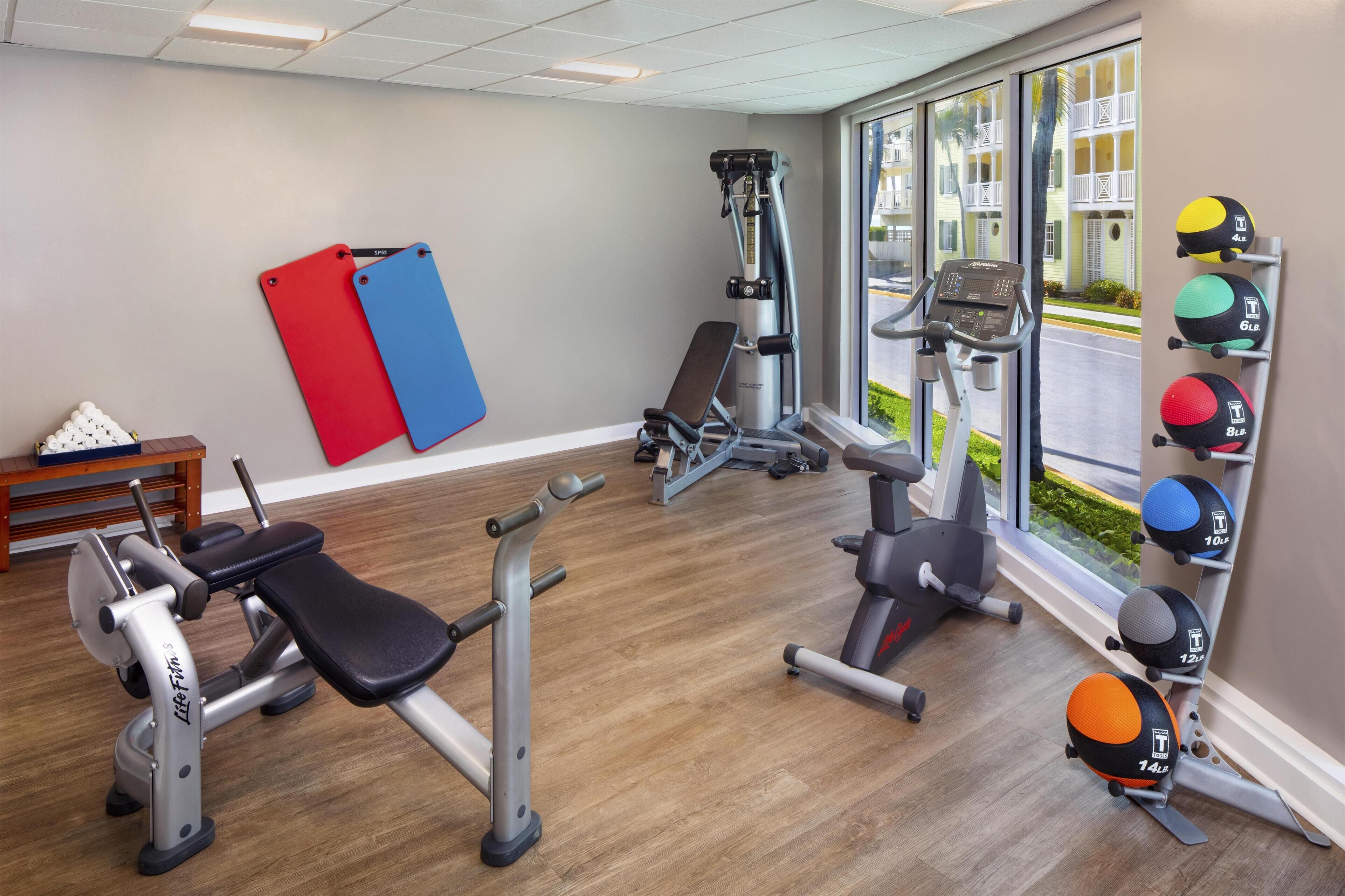 A gym with various exercise equipment, a bench, and a rack of medicine balls.
