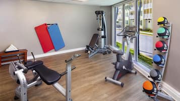 A gym with various exercise equipment, a bench, and a rack of medicine balls.