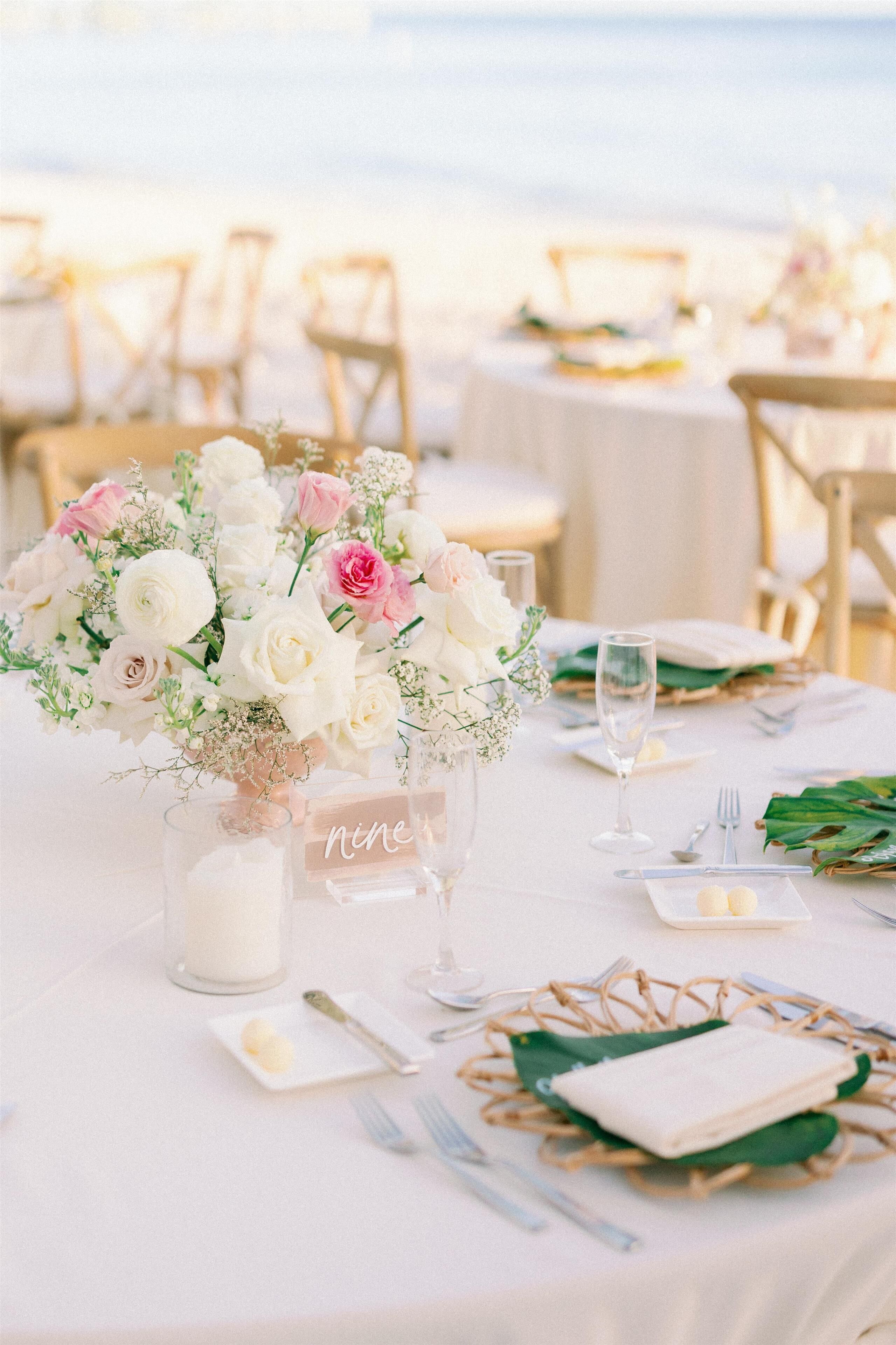 A table set for a meal with a floral centerpiece, a candle, and a sign reading "nine".