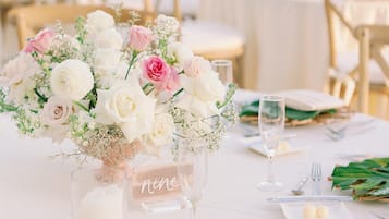 A table set for a meal with a floral centerpiece, a candle, and a sign reading "nine".