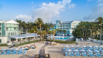 Relax on the beach with a pool and lounge chairs nearby.