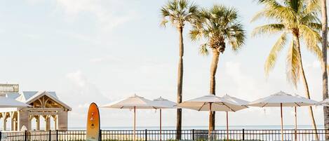 A poolside area with lounge chairs, umbrellas, and a surfboard.