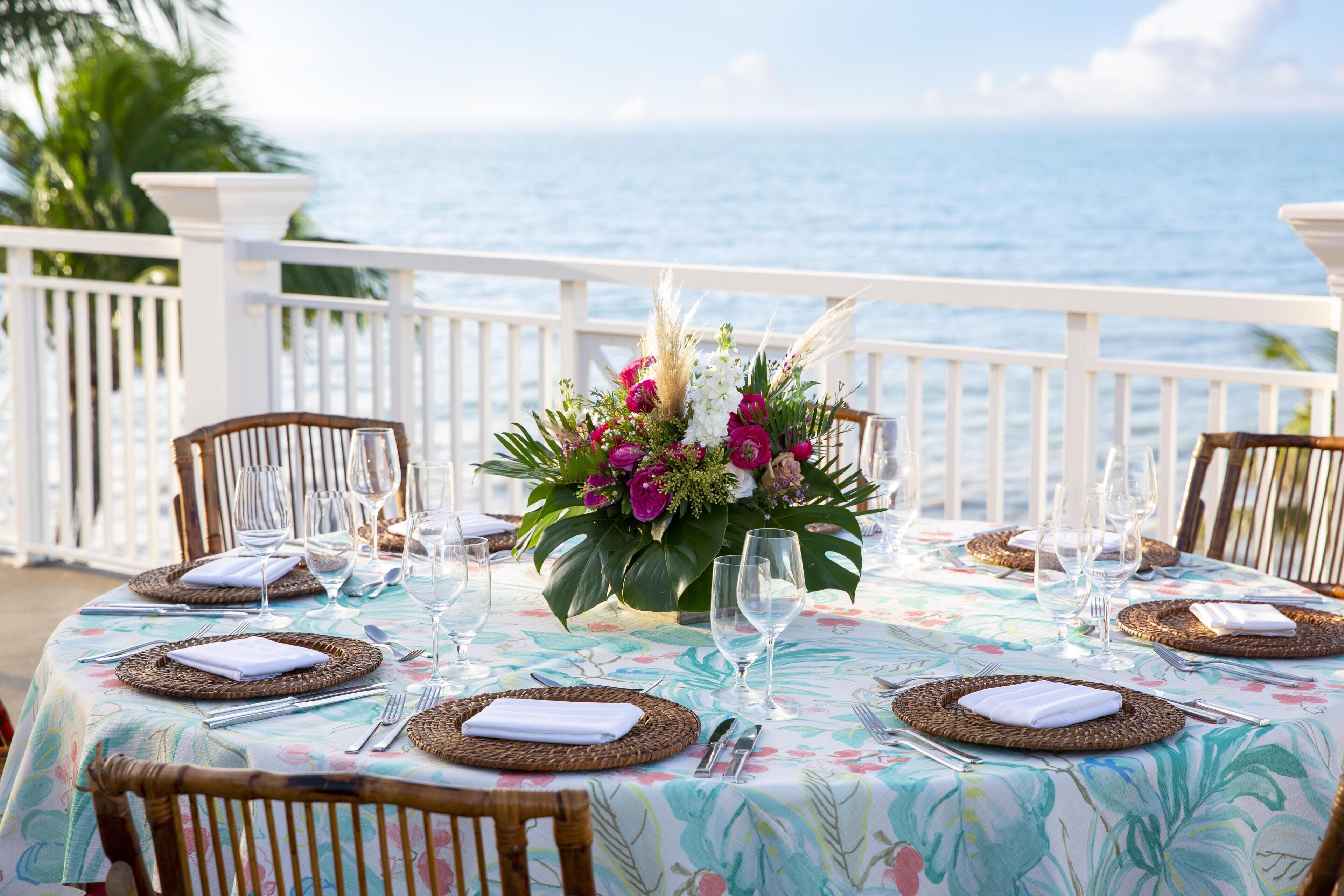 A table set for a meal with a floral tablecloth, white napkins, and a centerpiece of flowers.