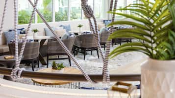 Un espace de détente intérieur moderne, avec des meubles en osier, une table ronde et une plante en pot.