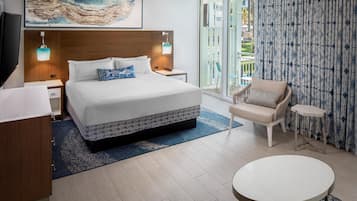 Une chambre d’hôtel moderne avec un grand lit, une petite table ronde, une chaise et un balcon avec vue.