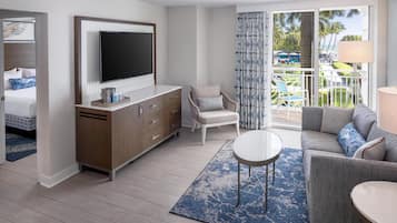 Una habitación de hotel moderna con televisor de pantalla plana, un sofá, una silla y una mesa de comedor.