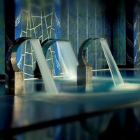 A modern architectural structure with curved metal elements and a reflective surface.