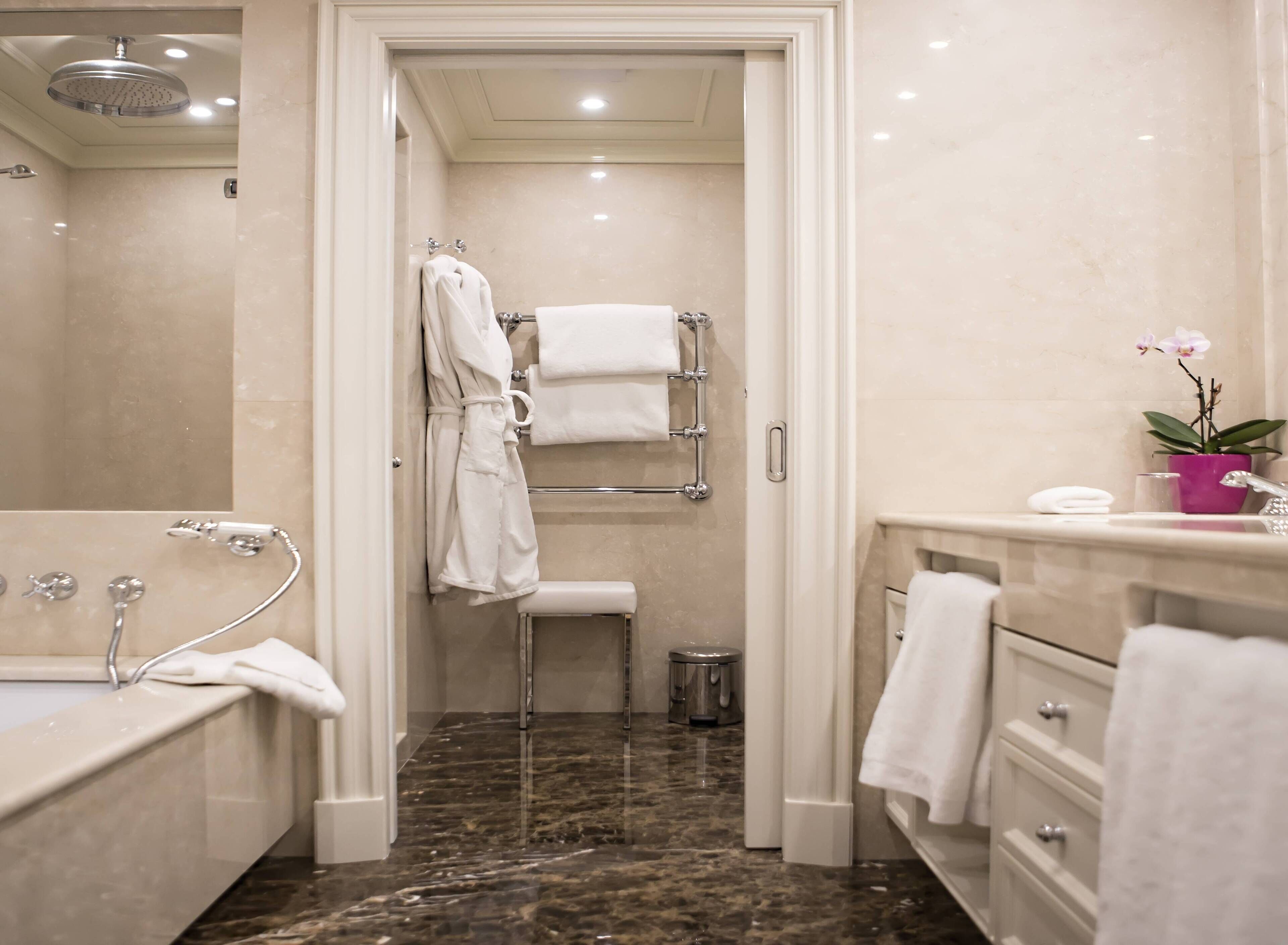 Un bagno moderno con doccia a filo pavimento, vasca da bagno, WC e un mobile lavabo con lavandino e specchio.