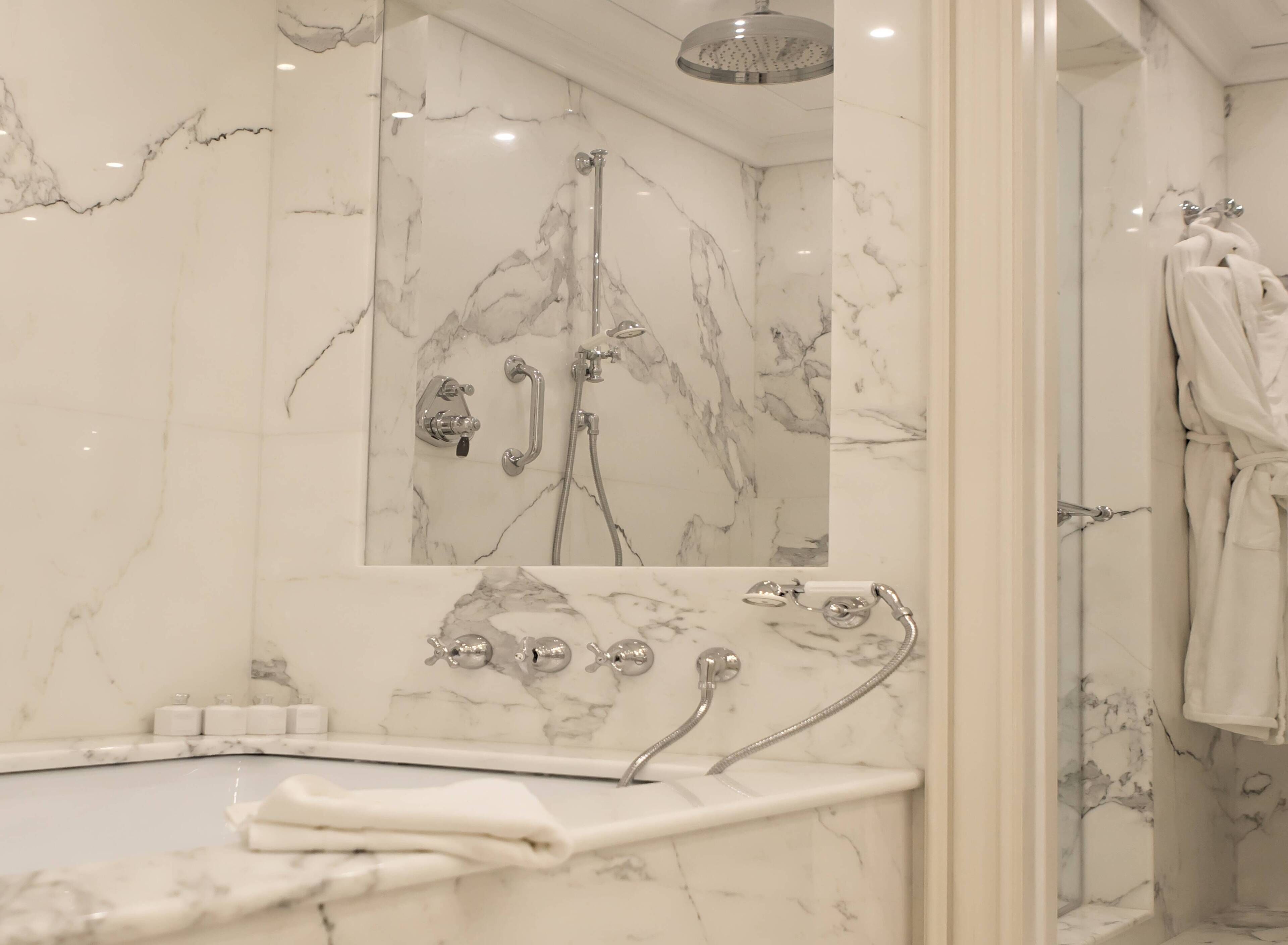 Une salle de bain avec un lavabo en marbre, une douchette à main et un porte-serviettes.