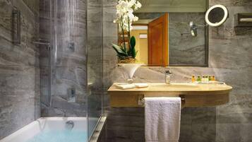 Un bagno moderno con doccia a vetro, vasca da bagno indipendente, un vanità in marmo con lavabo e uno specchio.
