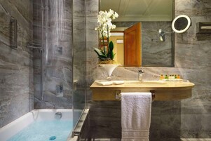 Un bagno moderno con doccia a vetro, vasca da bagno indipendente, un vanità in marmo con lavabo e uno specchio.