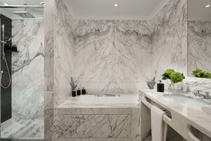 A modern bathroom with a marble wall, a bathtub, and a shower.