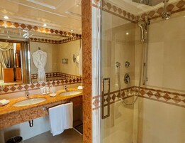 Un bagno con due lavandini, una cabina doccia in vetro e un grande specchio con un accappatoio appeso.