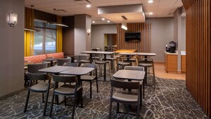 A modern dining area with multiple tables and chairs, a sofa, and a kitchen area with a coffee machine. - Sonesta Select Nashville Airport Suites (Nashville)