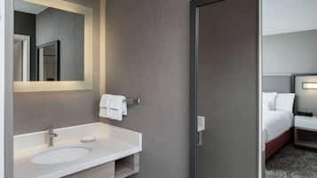 A modern bathroom with a white sink, mirror, and towel rack.