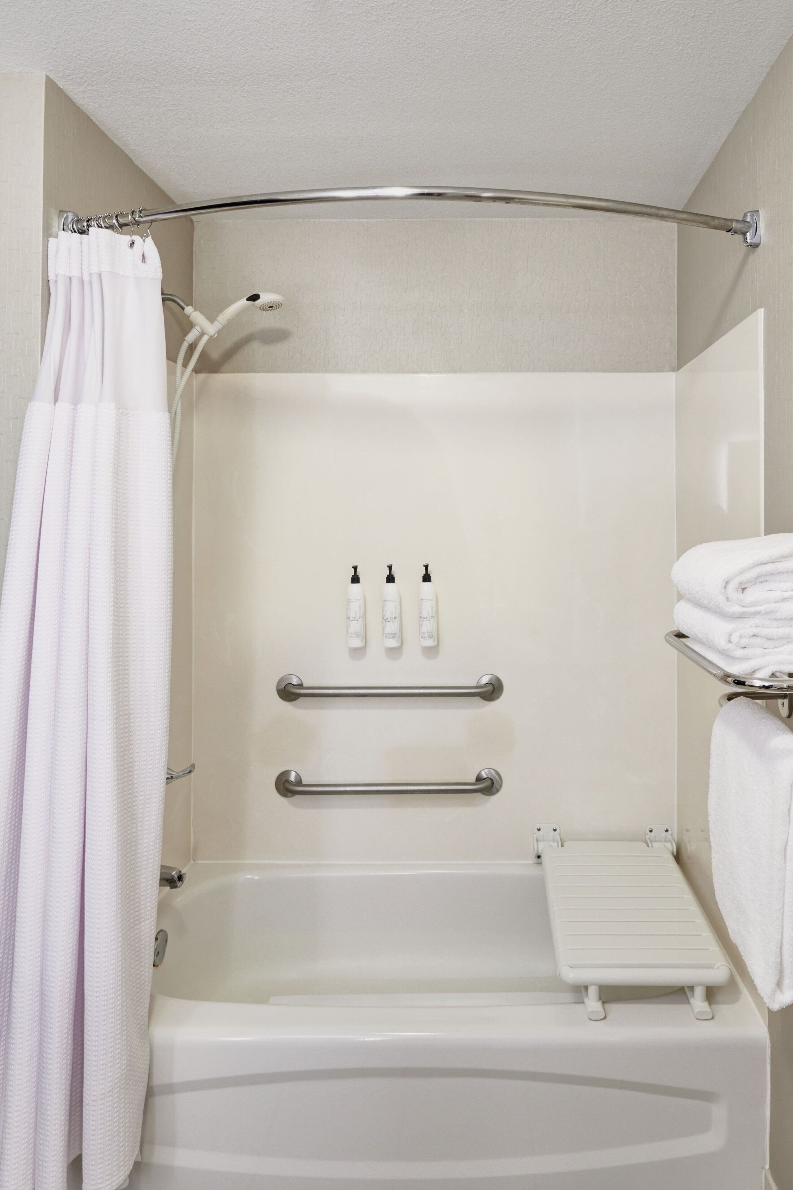 A modern bathroom with a bathtub, grab bars, a shower curtain, and a towel rack.