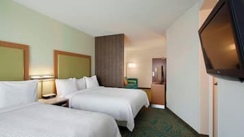 A hotel room with two beds, a television, a desk, and a chair.