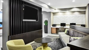 A modern lobby with a flat-screen TV, a sofa, a round table, and a reception desk.