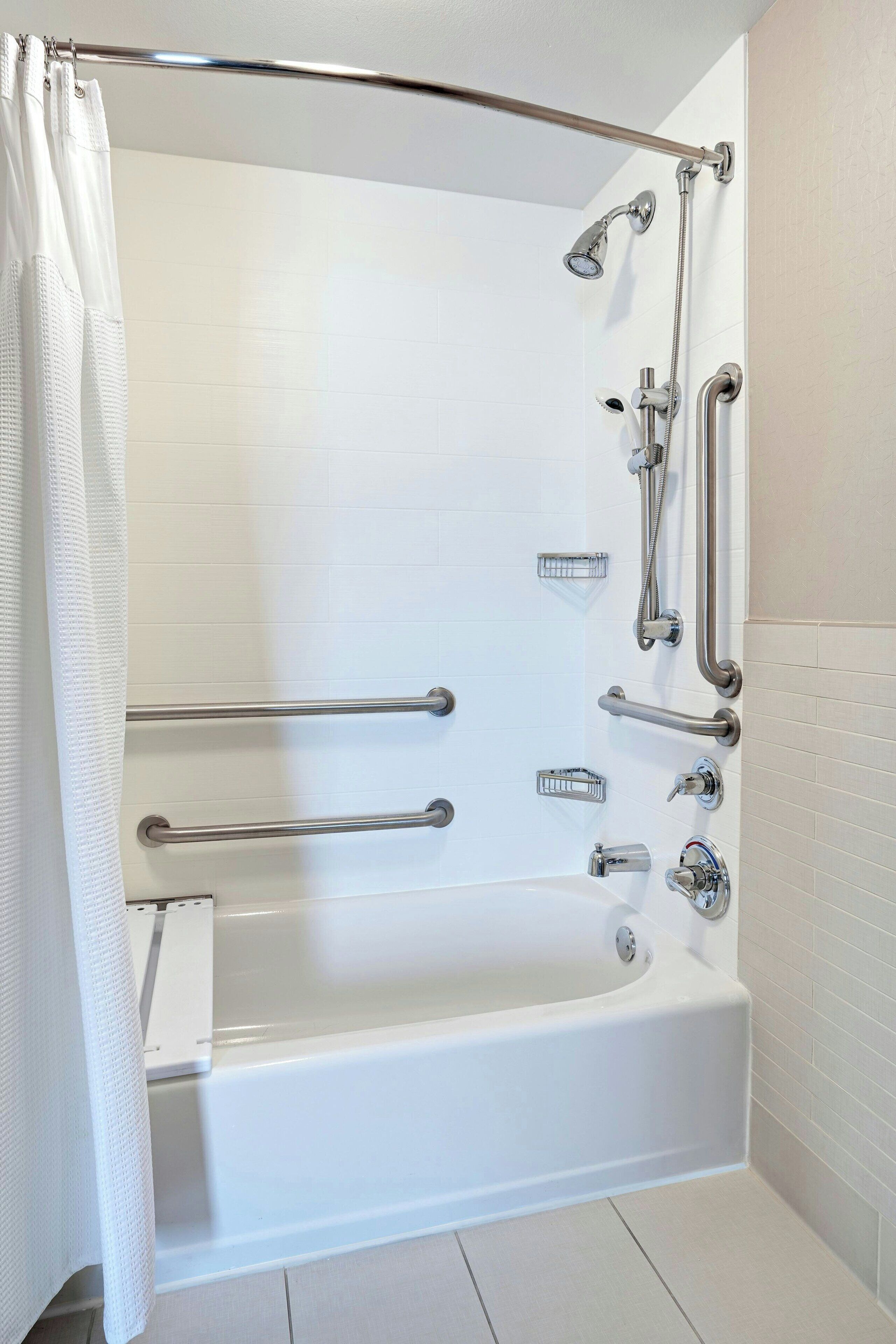 Une salle de bain moderne équipée d’une baignoire, d’une douche et de barres d’appui.