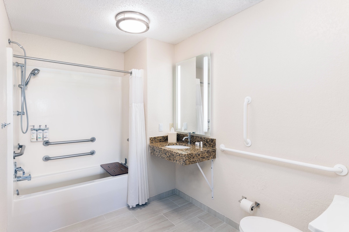 Un baño moderno con bañera, lavabo, inodoro y espejo.