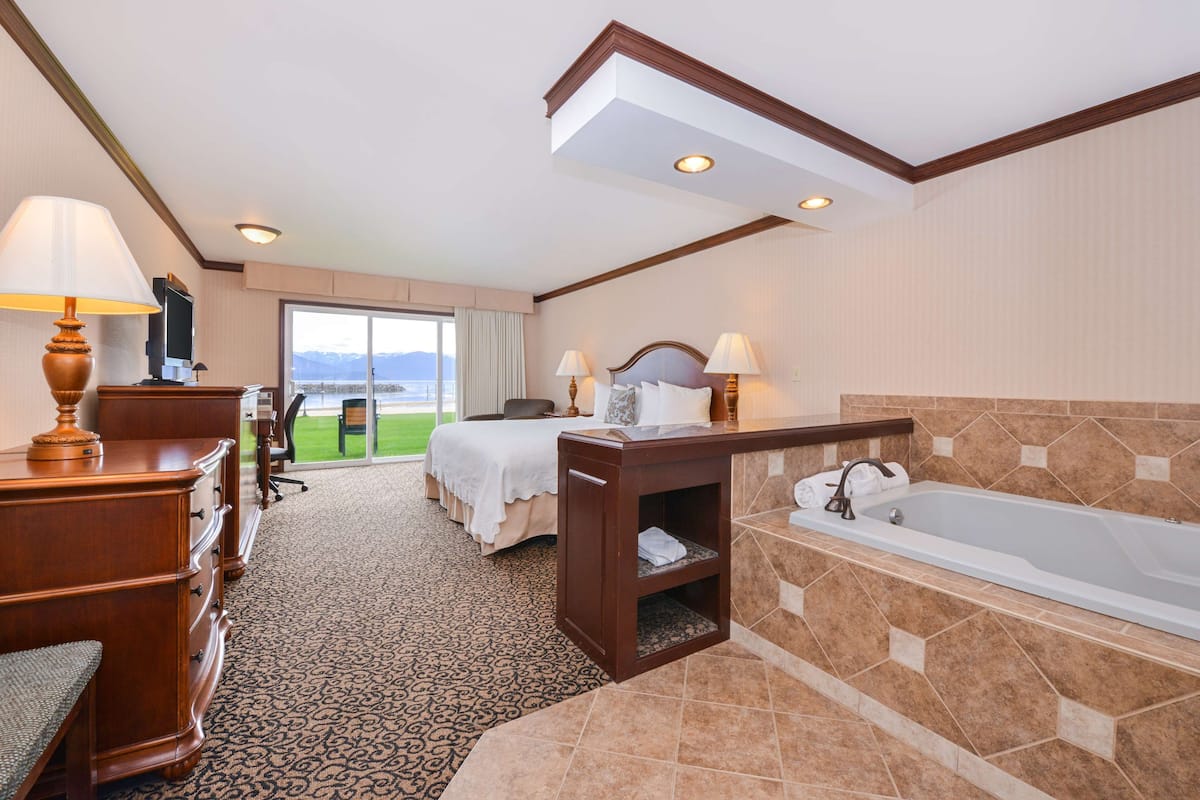 Habitación de hotel con cama, escritorio, silla y una bañera grande.