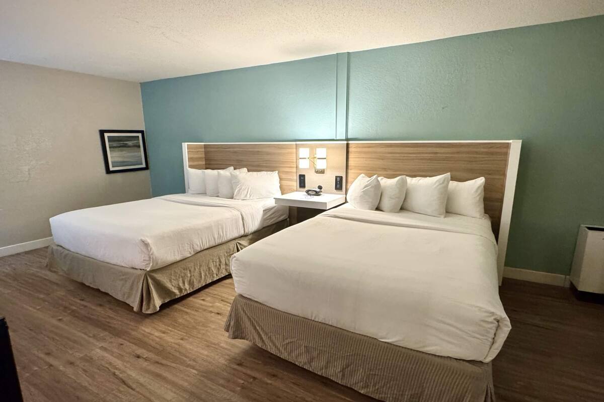 Ein Hotelzimmer mit zwei Betten, einem Nachttisch und einer wandmontierten Lampe.