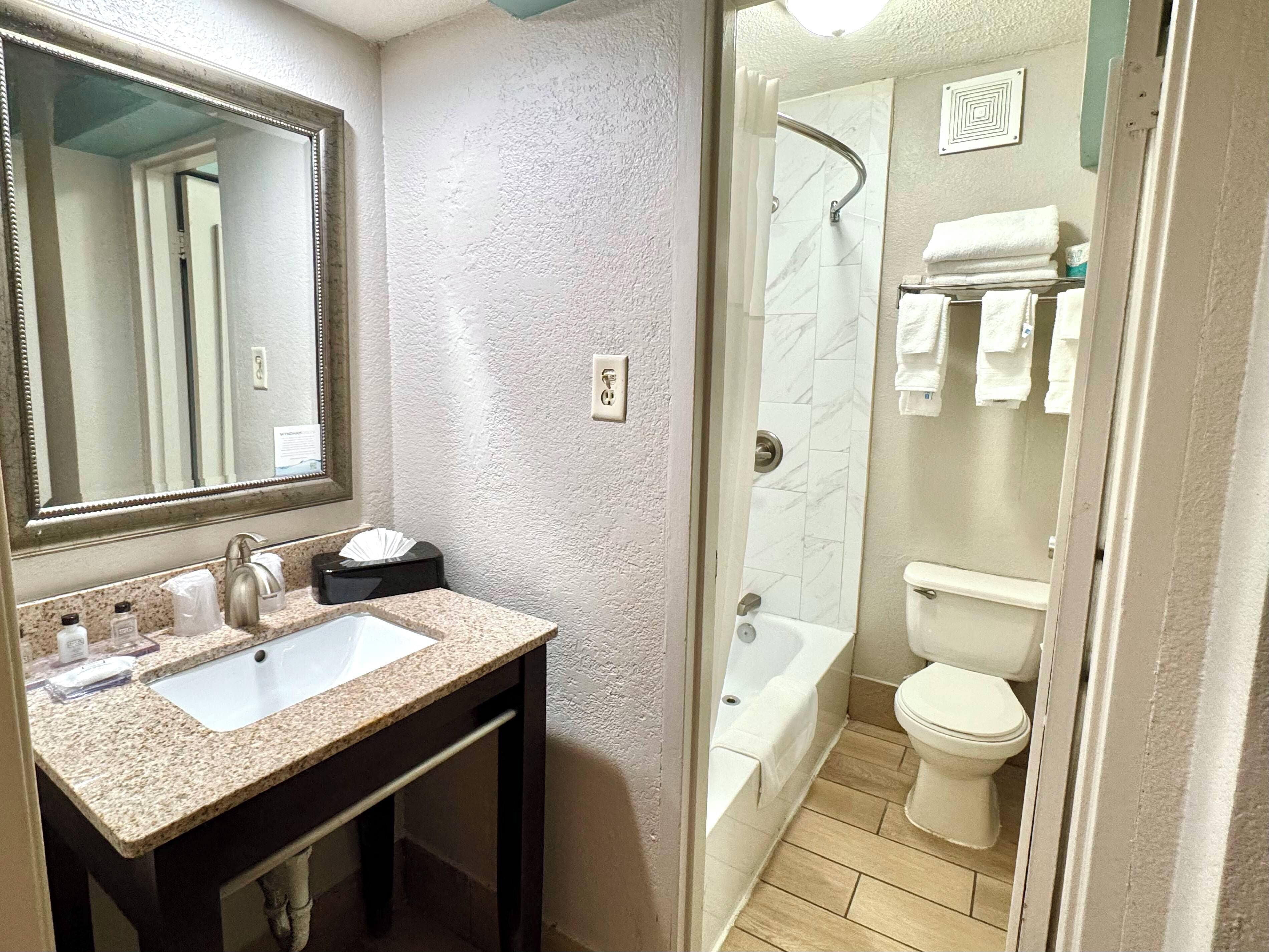 A bathroom with a sink, mirror, and shower area.