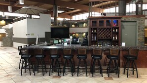 Un espace bar doté d’un comptoir haut, de plusieurs tabourets et d’un présentoir à vins.