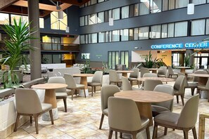 A spacious indoor area with multiple tables and chairs, a visible elevator, and a sign for the conference center.