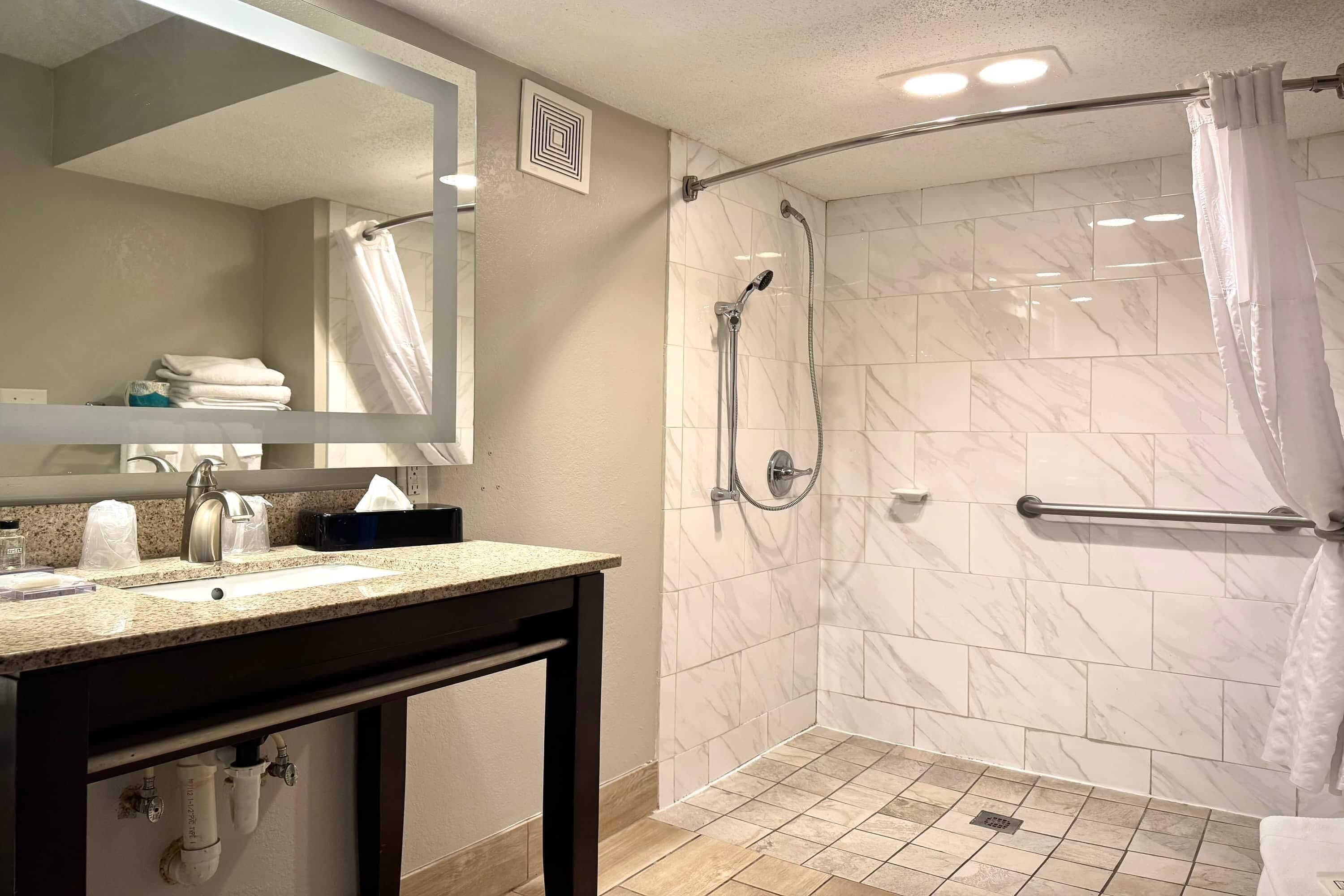 Ein modernes Badezimmer mit Waschbecken, Spiegel und Dusche.