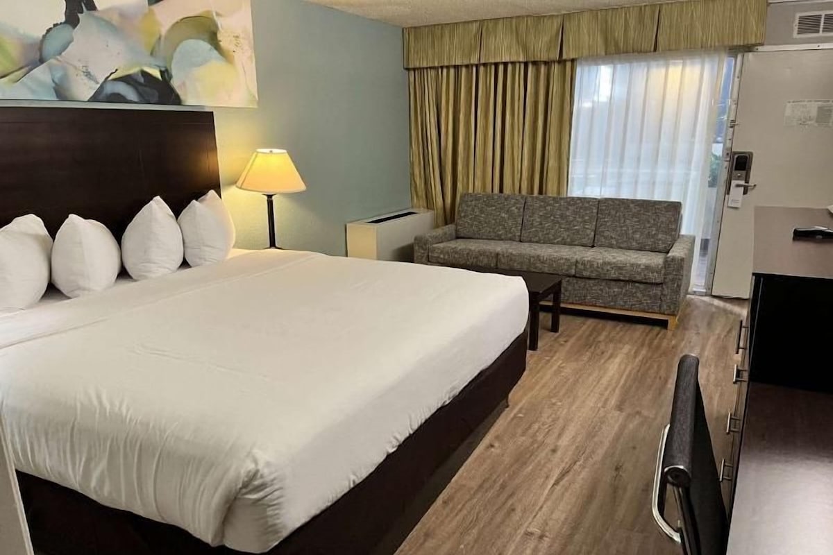 Een hotelkamer met een groot bed, een bank, een lamp en een schilderij aan de muur.