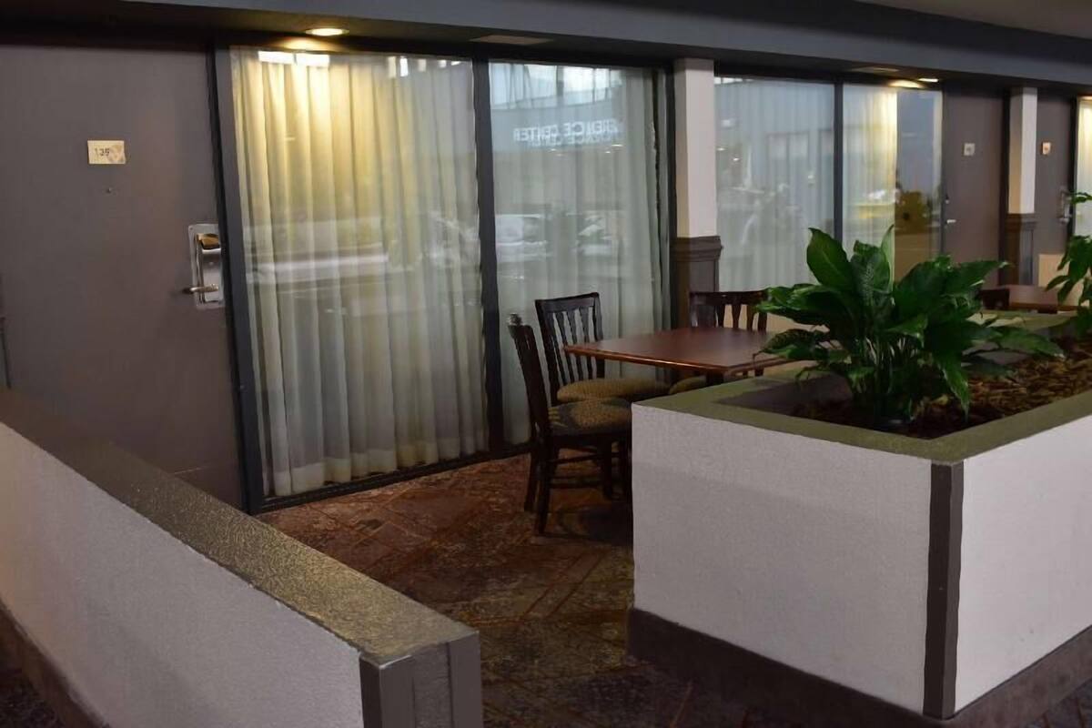 Ein Zimmer mit einer Schiebetür, einem Holztisch, einem Stuhl und einem Blumentopf.