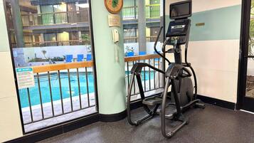 Ein Fitnessbereich mit Laufband, Blick auf den Pool und einem Hinweisschild für Unterstützung.
