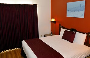 Relax in comfort with a large bed, a nightstand, and a warm accent wall.