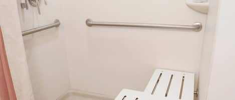 A bathroom with a shower, grab bars, and a white toilet.