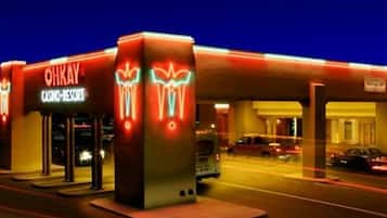 A brightly lit gas station with neon signs and a visible car in the background.