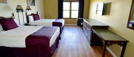 Habitación de hotel con dos camas, un escritorio, una cómoda y una ventana con cortinas.