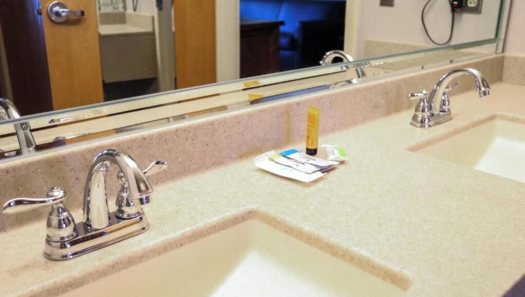 A bathroom with two sinks, a mirror, and a paper towel dispenser.