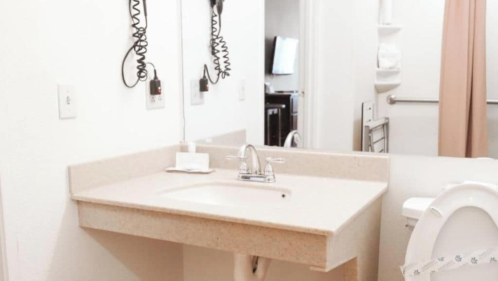 A bathroom with a sink, mirror, and toilet.