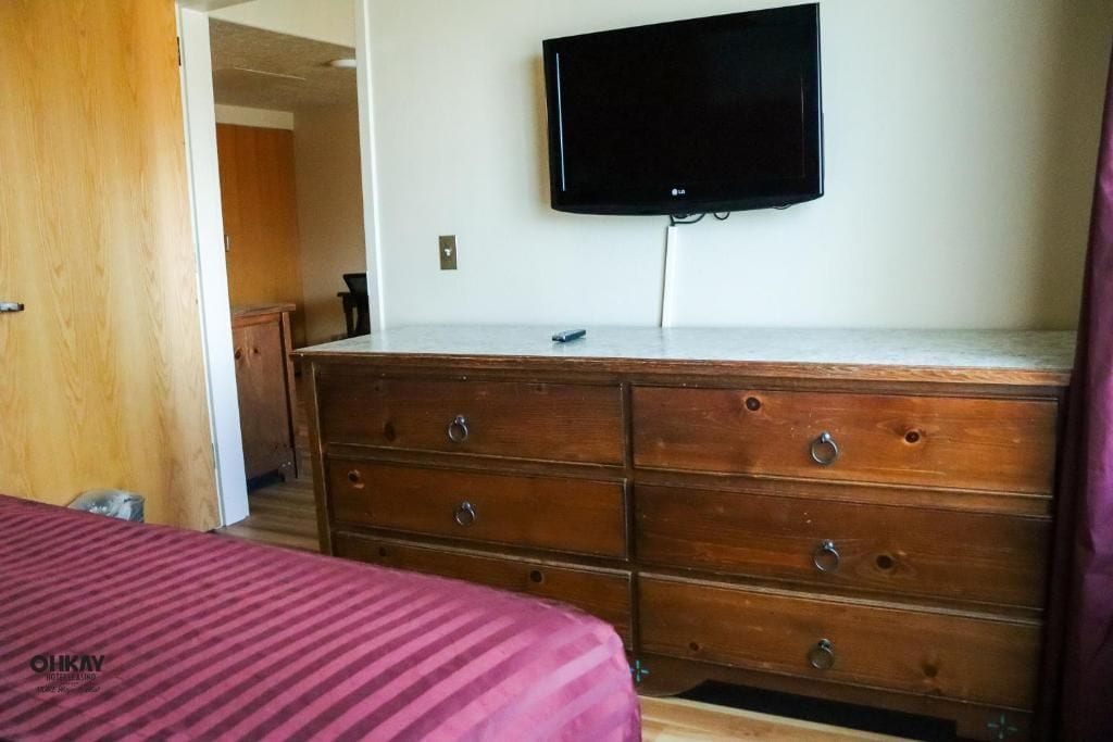 A bedroom with a bed, a dresser, and a television mounted on the wall.