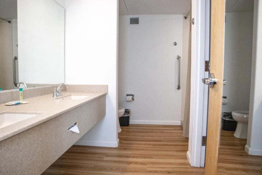 A bathroom with a sink, mirror, and shower area.