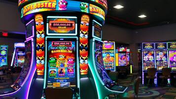A casino slot machine area with multiple machines, chairs, and a carpeted floor.