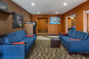 Un hall de hotel con dos sofás azules, un mostrador de recepción y un cuadro con una vista de la ciudad.
