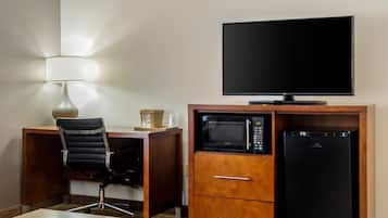 Ein Hotelzimmer mit Schreibtisch, Stuhl, Flachbildfernseher, Mikrowelle und Kühlschrank.