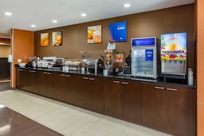 A breakfast bar with coffee machines, waffle makers, and a juice dispenser.
